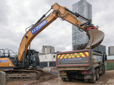 Excavator loading material into a dump truck on a construction site